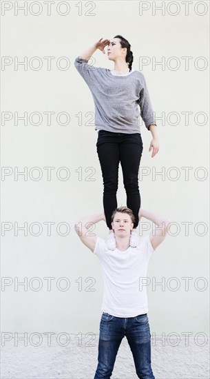 Woman standing on shoulders of man looking away