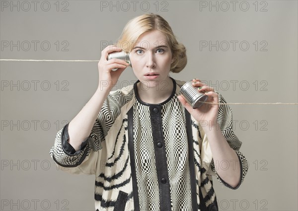 Blond woman listening with tin can phone