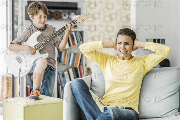 Mother sits on the couch in the living room and covers her ears