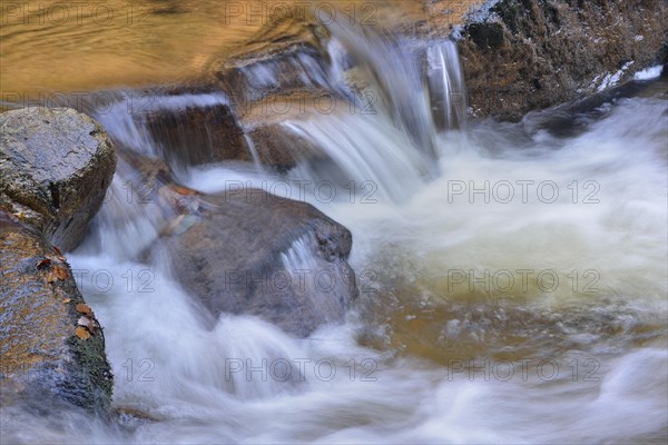 Water running over rocks in a brook in autumn