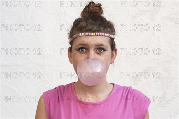 Teenage girl with a gum bubble in front of her face