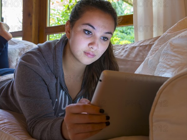 Girl reading on a tablet computer at home