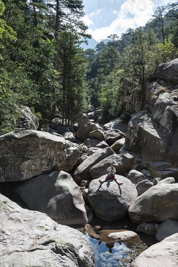 Young man sitting on rocks at the Calenzana river
