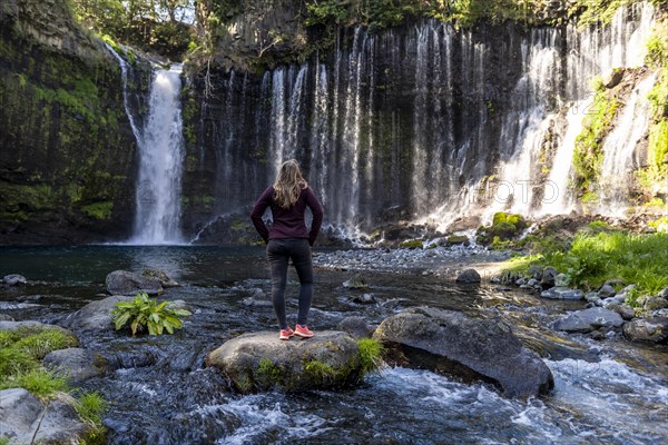 Young woman standing on a stone in a river