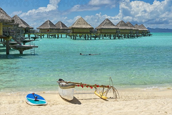 Decorated outrigger boat in front of overwater bungalows
