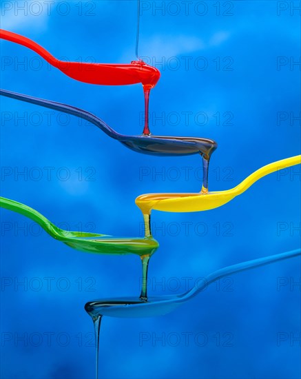 Colourful spoons with honey changing colour as it flows down through them