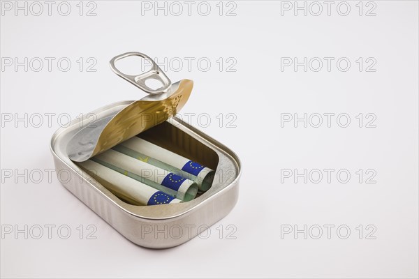 Three rolled-up 100 Euro banknotes inside a silver aluminum can on white background