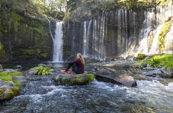 Young woman sitting on a stone in a river