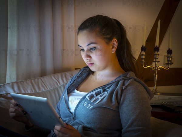 Girl reading on a tablet computer at home