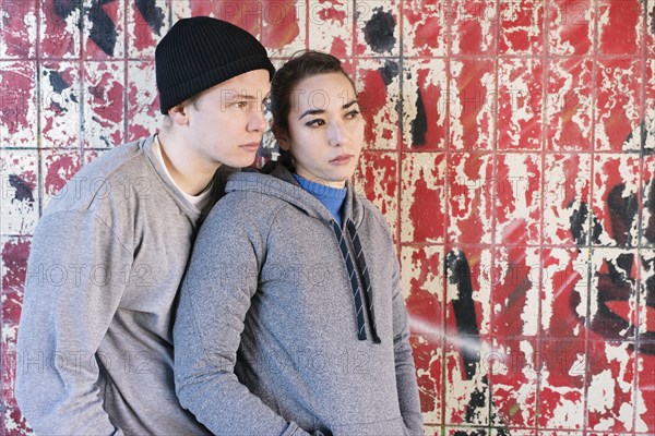 Casual and relaxed young man and woman waiting in front of grafitti wall in urban area