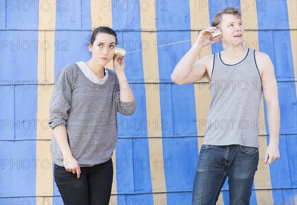 Young woman and young man with a tin can phone