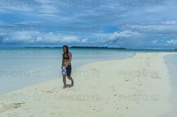 Tourist walking on a sand strip at low tide