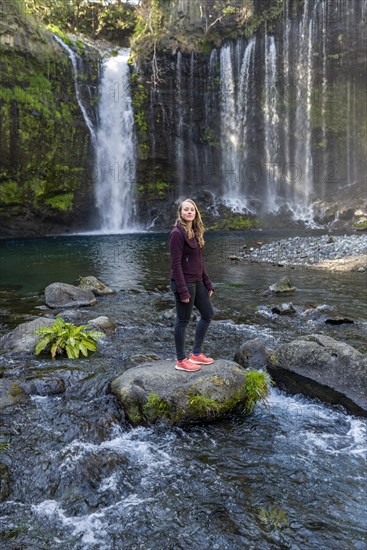 Young woman standing on a stone in a river