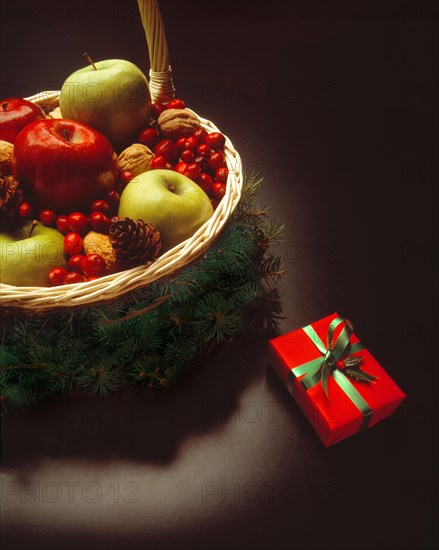 Christmas present beside festive basket filled with fruits and nuts