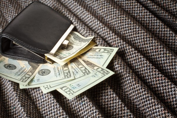 Leather coin purse on a plaited tweed skirt with money strewn around