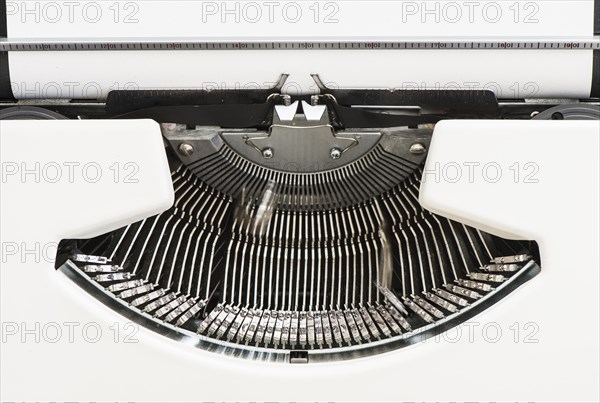 Detail view of an old fashioned typewriter from the 1970s with blank paper and moving hammer heads
