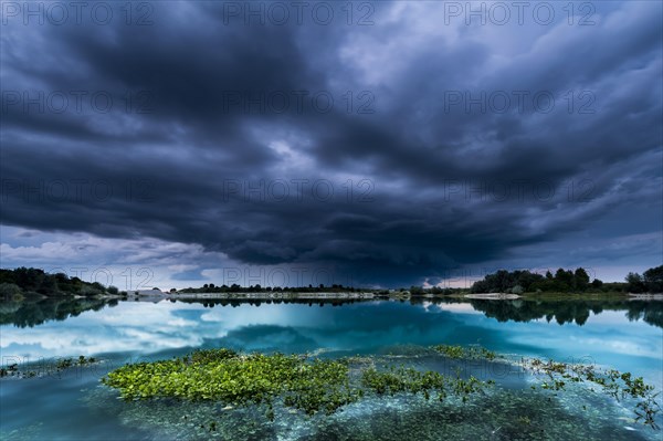 Storm clouds over a quarry lake with water plants