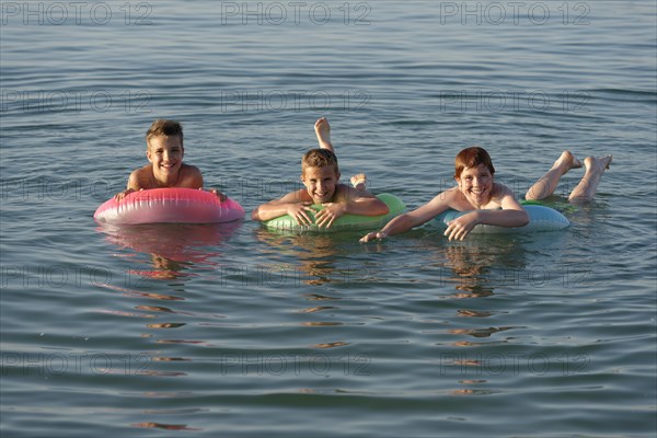 Children on floating tyres in the sea