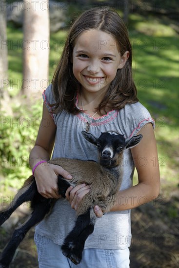 Girl holding a dwarf goat in the petting zoo at Schopperalm