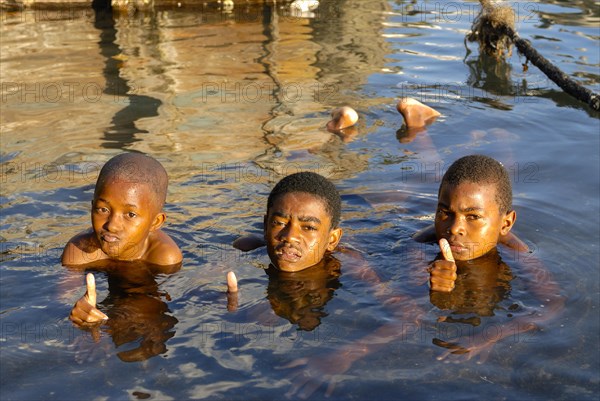 Three boys in the water showing a thumbs up