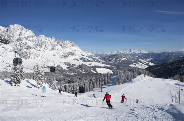 Skiers on ski slope in front of mountain scenery