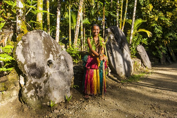 Traditionally dressed girl standing in front of stone money