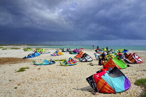 Kites and kitesurfers on the beach in high winds