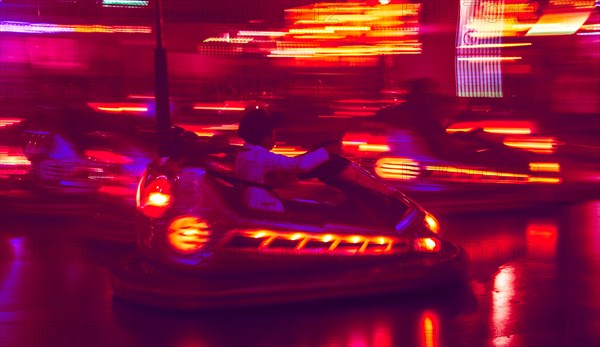 Little boy driving bumper car at night