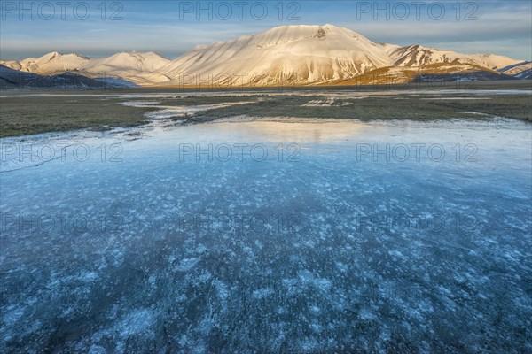 Monte Vettore in the evening light with a frozen puddle with air bubbles