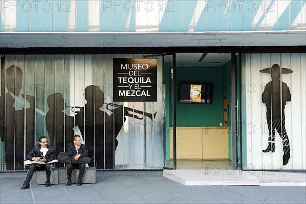 Mariachi musicians with violins sitting in front of the Museo del Tequila y el Mezcal