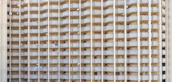 Facade of a skyscraper with satellite dishes on balconies