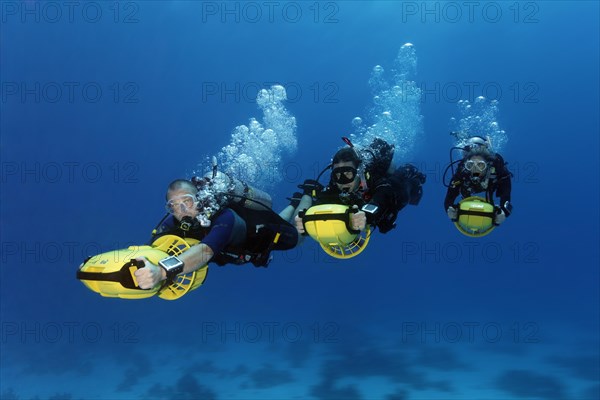 Divers with diver propulsion vehicles exploring a coral reef