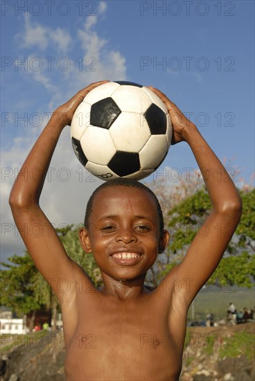 Smiling boy holding a football on his head