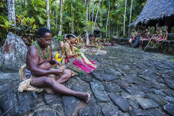 Traditionally dressed islanders making traditional art work