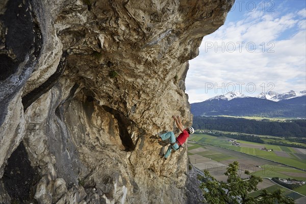 Freeclimber with helmet climbing on a rock face