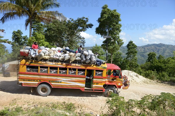 Overcrowded bus on a dusty road in the mountains