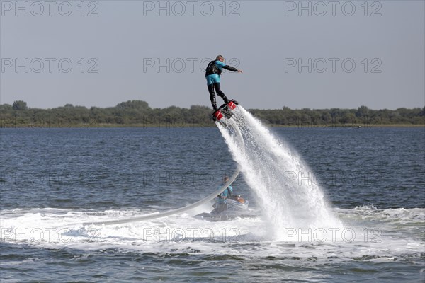 Flyboarder on the water jet of a jet ski