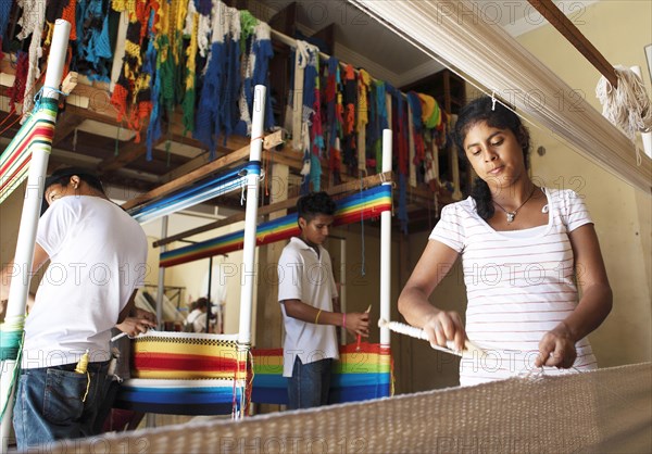 Woman and men weaving hammocks by hand