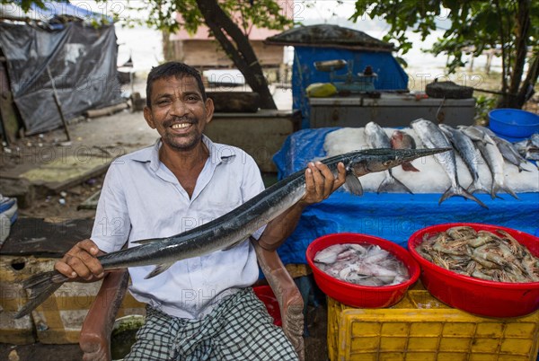 Fish seller holding a Freshwater Garfish (Xenentodon cancila)