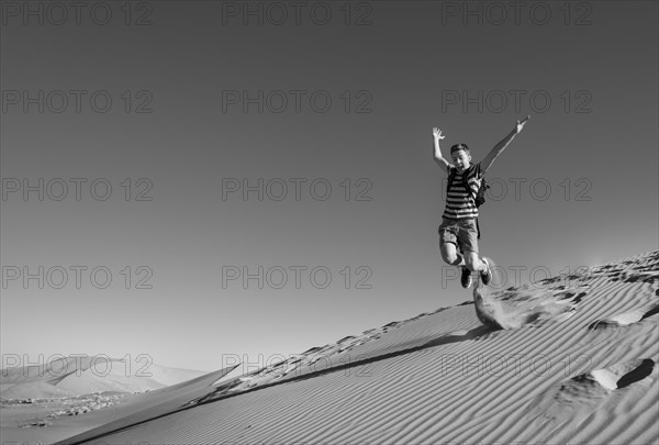 Teenager jumping and running down a dune