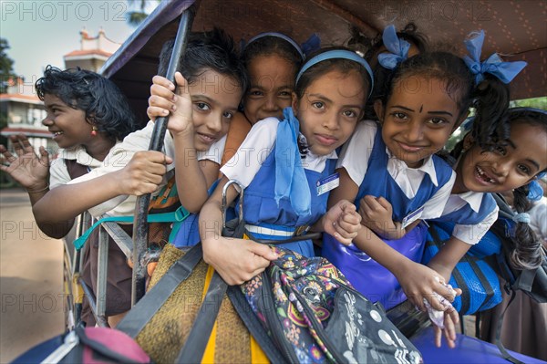 School children in school uniforms sitting in a rickshaw