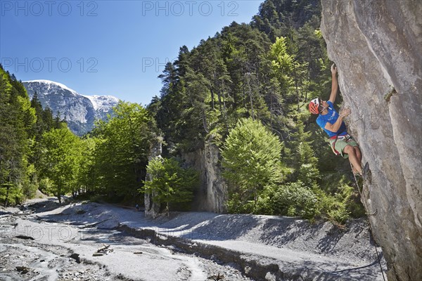 Sport climber wearing a helmet climbing a rock face