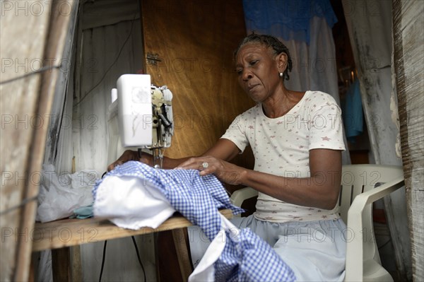 Seamstress working on a sewing machine in a hut