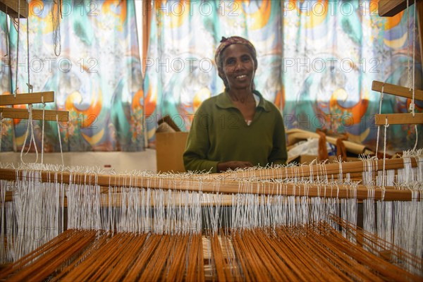 Friendly woman working on a hand weaving loom on social project