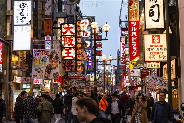 Crowd crowded in pedestrian zone with lots of illuminated advertising for restaurants and shopping centers