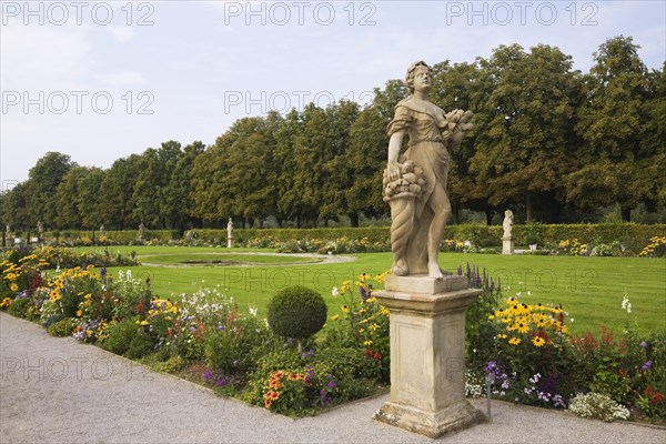 Statue and border with flowers and manicured lawn in the grounds of Schloss Weikersheim Palace garden in late summer