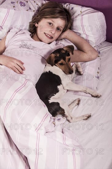 Girl lying in bed with a Danish Swedish Farmdog