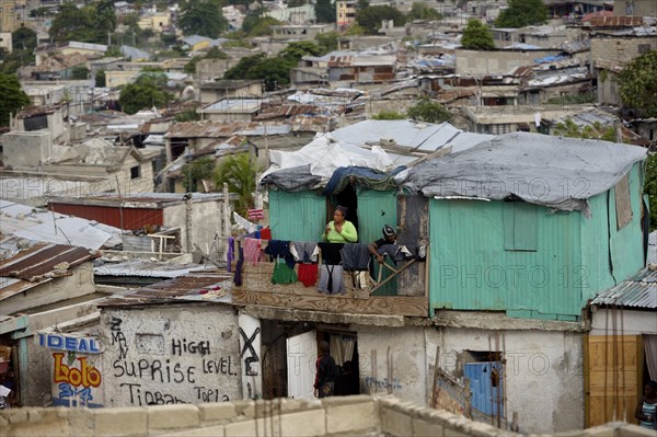 Woman on the balcony of her green-painted shack