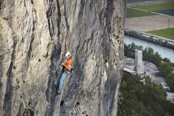 Freeclimber with helmet climbing on a rock face