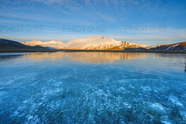 Monte Vettore in the evening light with a frozen puddle with air bubbles